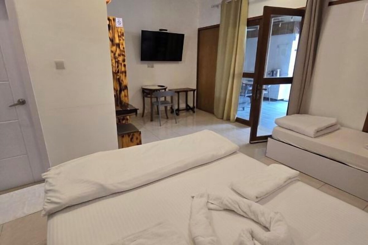 A hotel room with a bed, a sofa, a TV, a small table, and a chair.