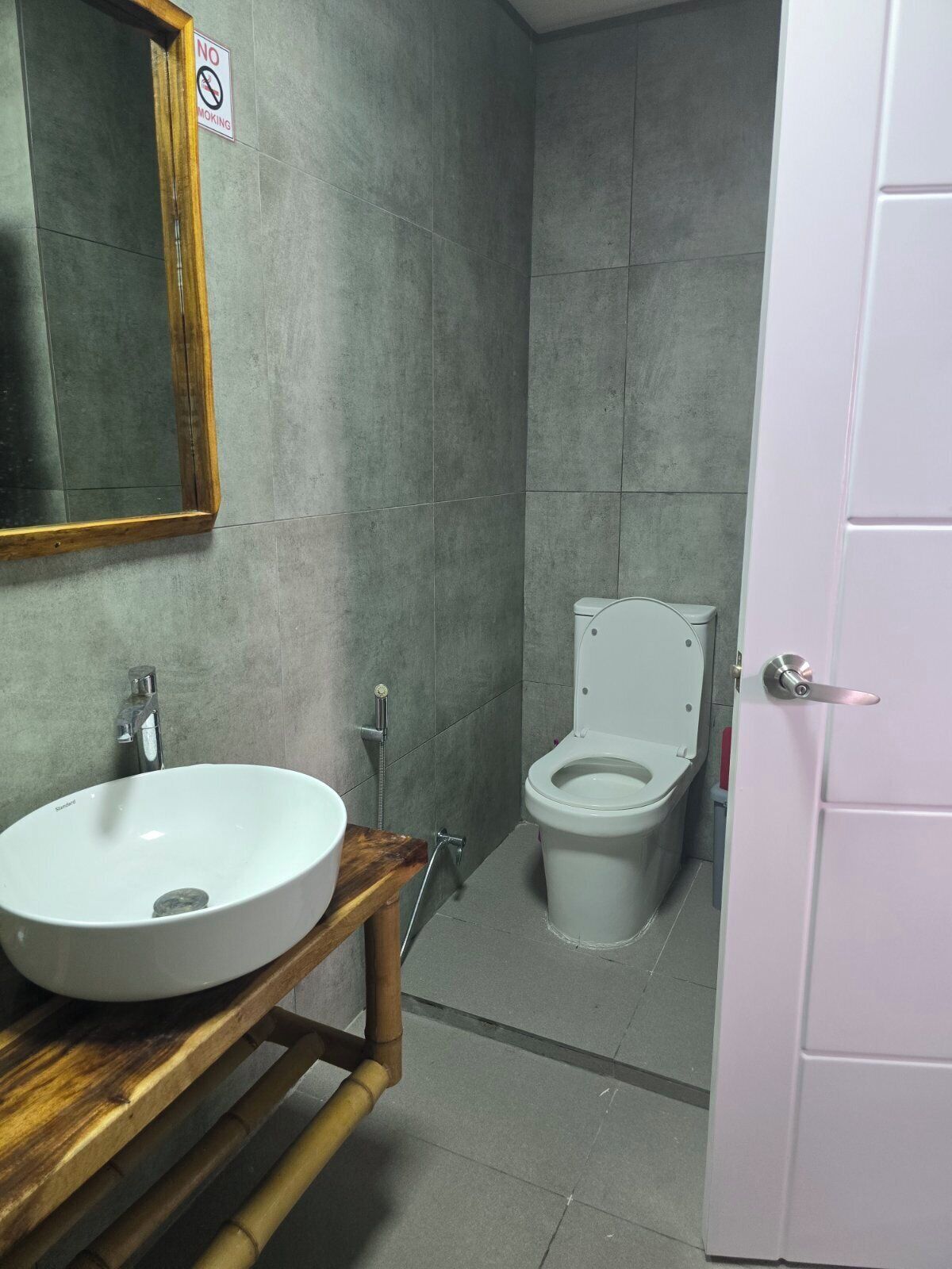 A bathroom with a white sink, a toilet, and a mirror on the wall.