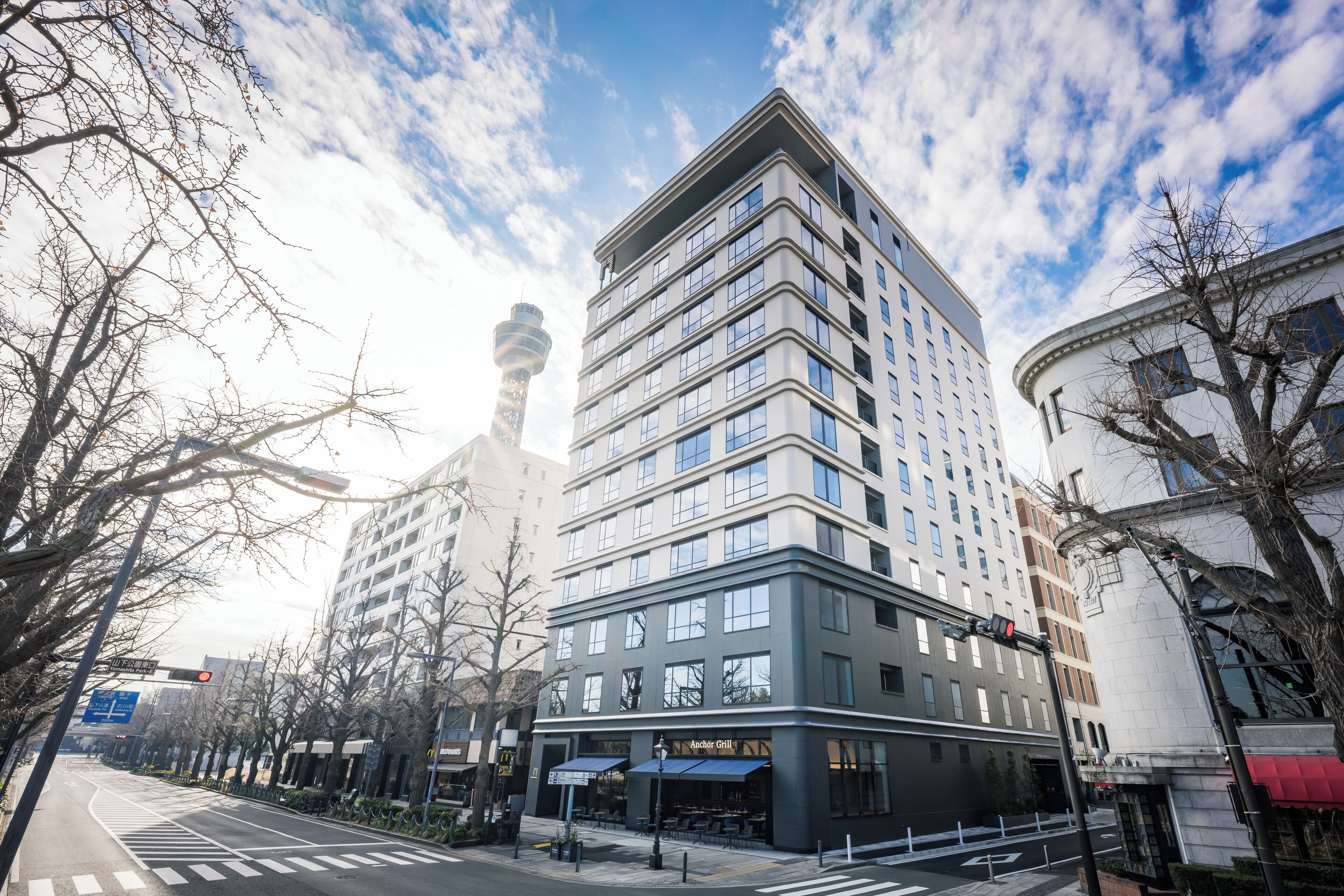 Un edificio de varios pisos con un diseño arquitectónico moderno, que destaca una entrada en esquina y el letrero visible de un restaurante.