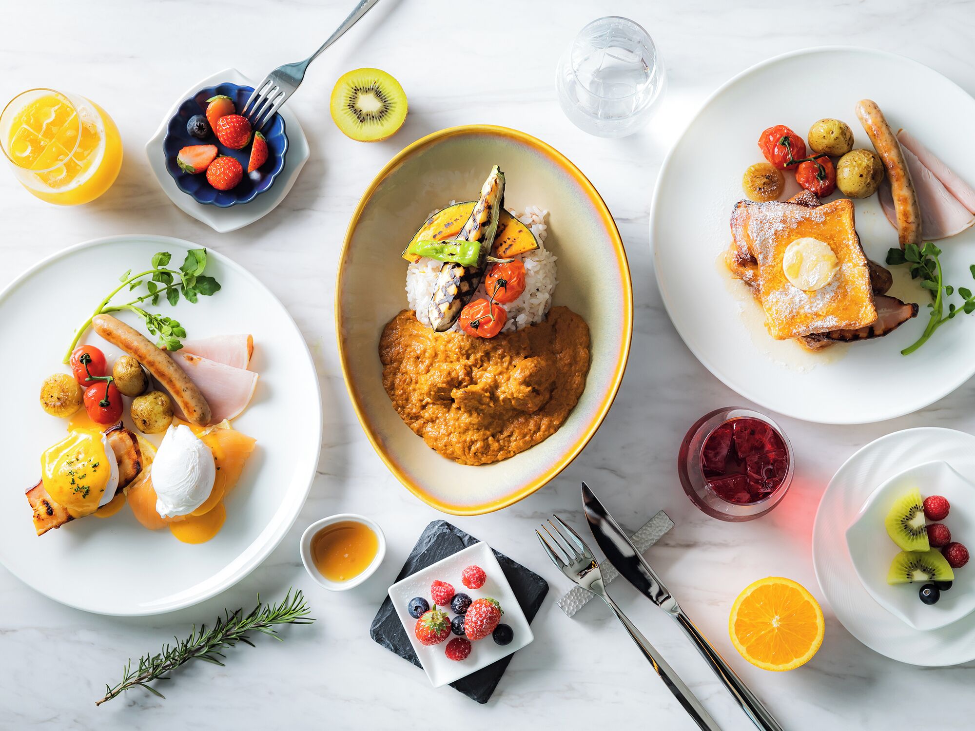 A breakfast setting with various dishes including pancakes, eggs, and fruits.