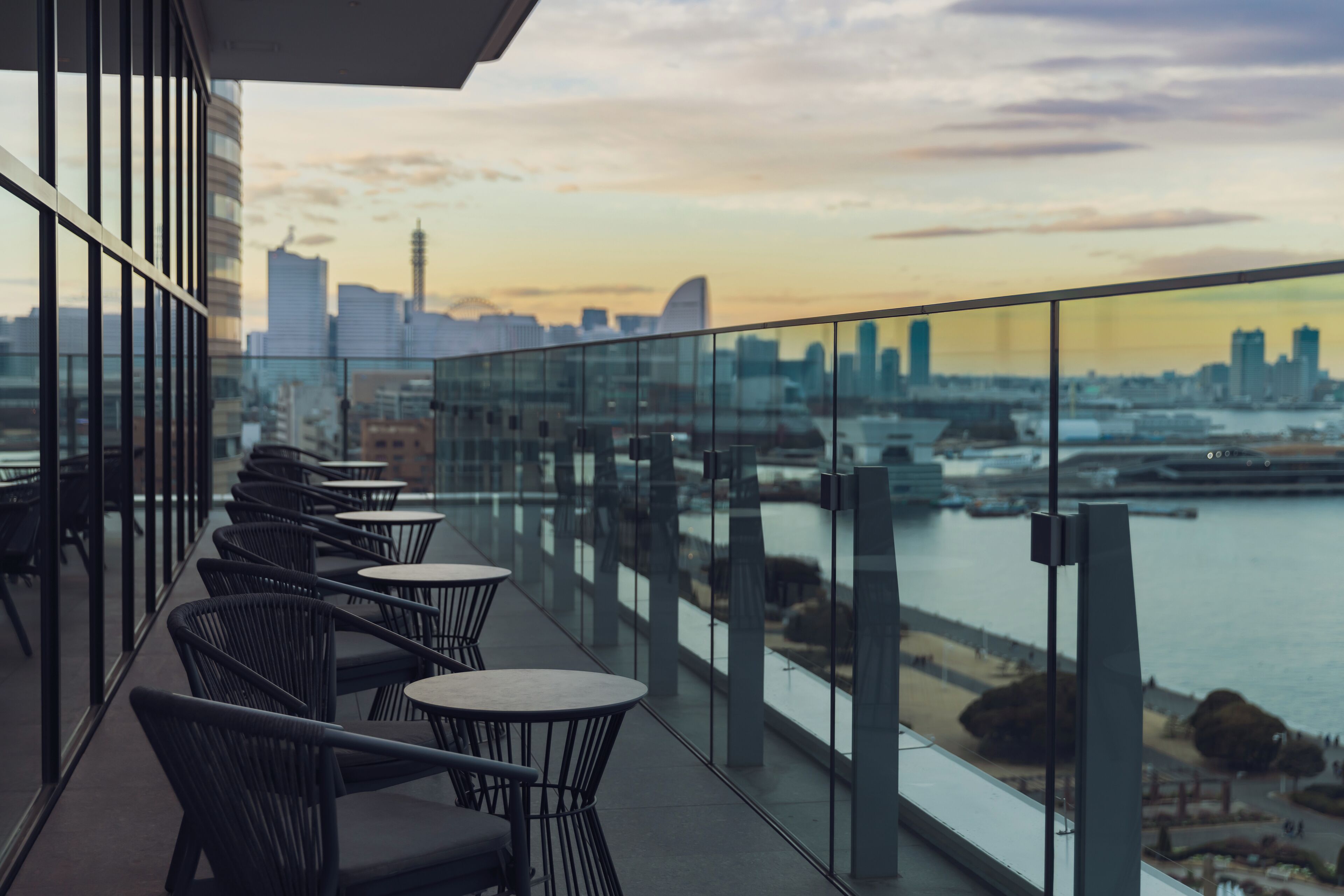 A balcony with a city skyline view, tables, and chairs.