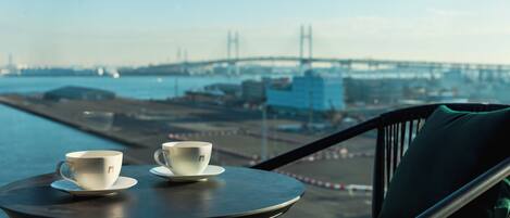 A balcony with two white cups on a saucer, overlooking a bridge and water.