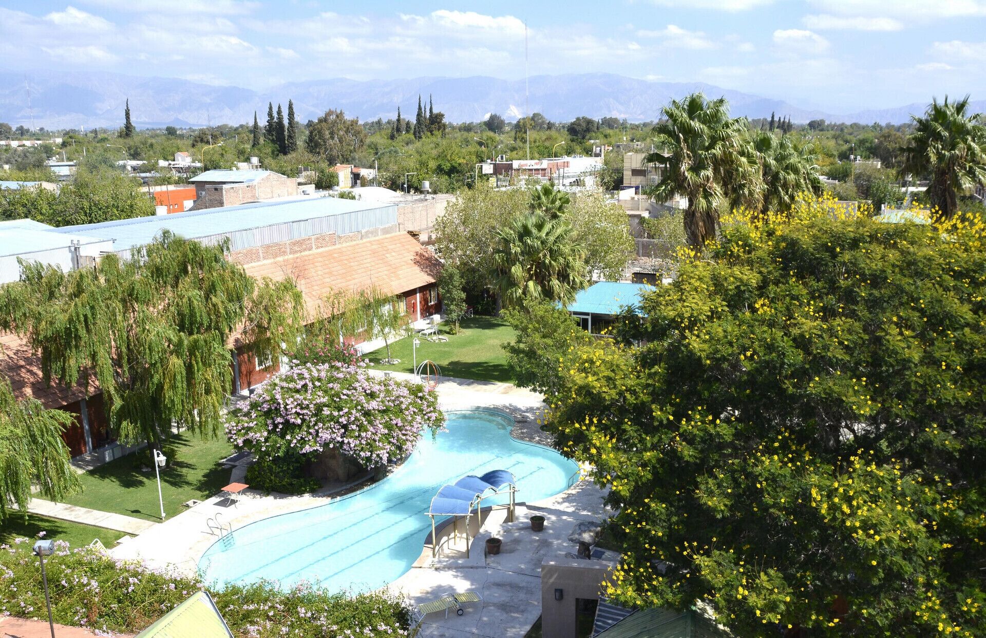 Un resort con piscina, un espacio techado y vistas a montañas lejanas.