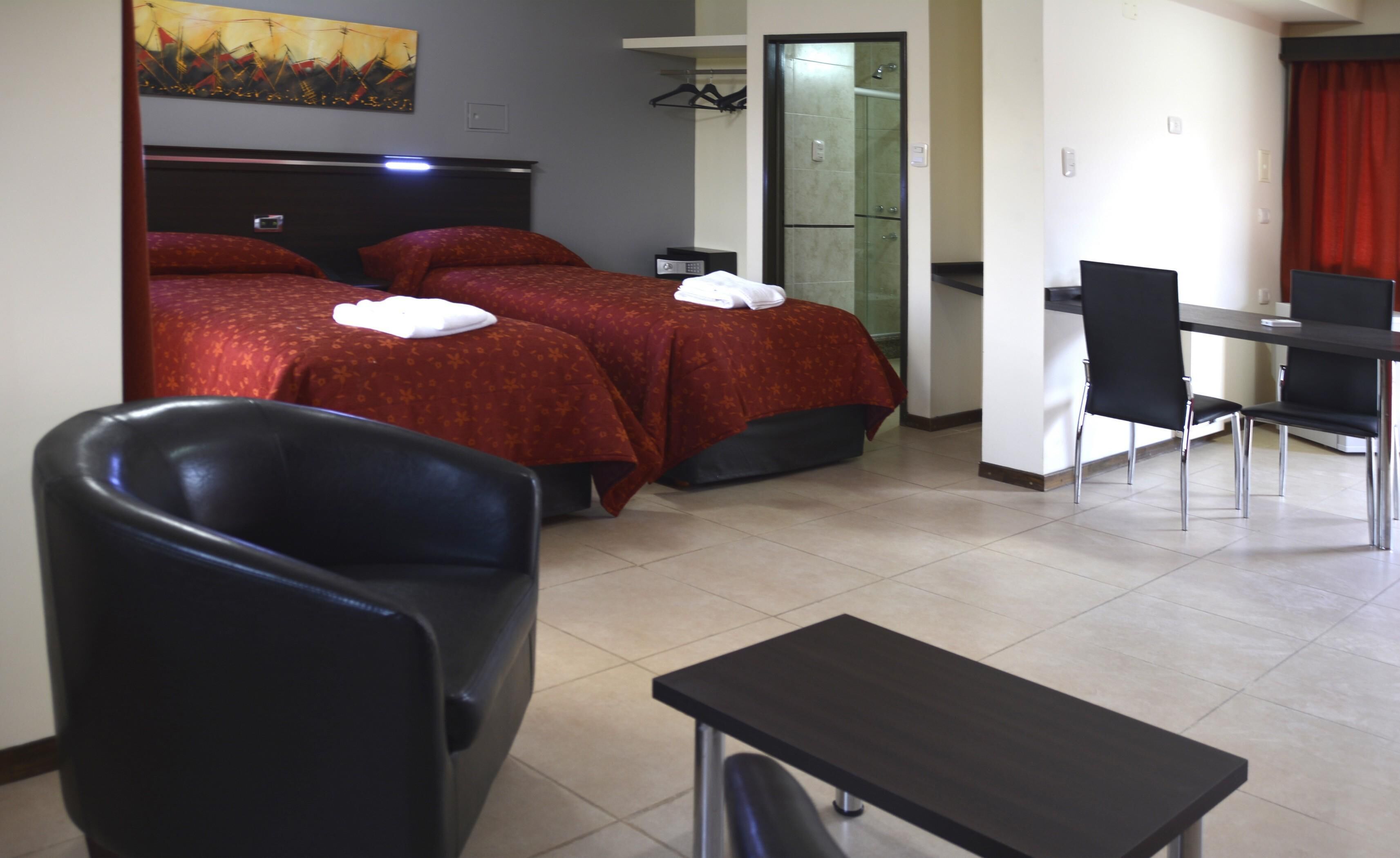 Une chambre d’hôtel avec deux lits, un bureau et une chaise.