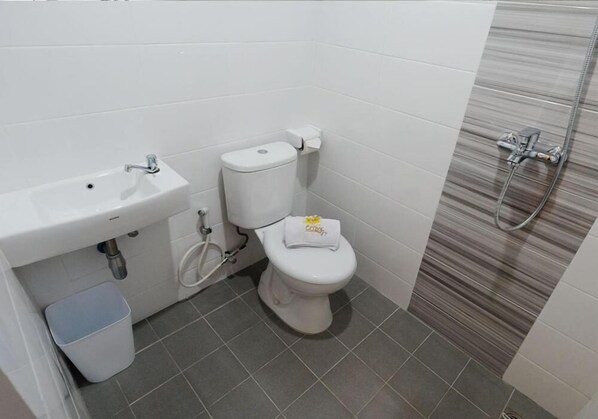 A small bathroom with a toilet, sink, and shower. - Cozzy Stay Semarang by Sinergi (Semarang)