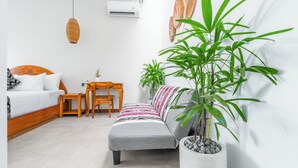 Una camera da letto moderna con un letto, un divano, una scrivania e un'ampia pianta in vaso.