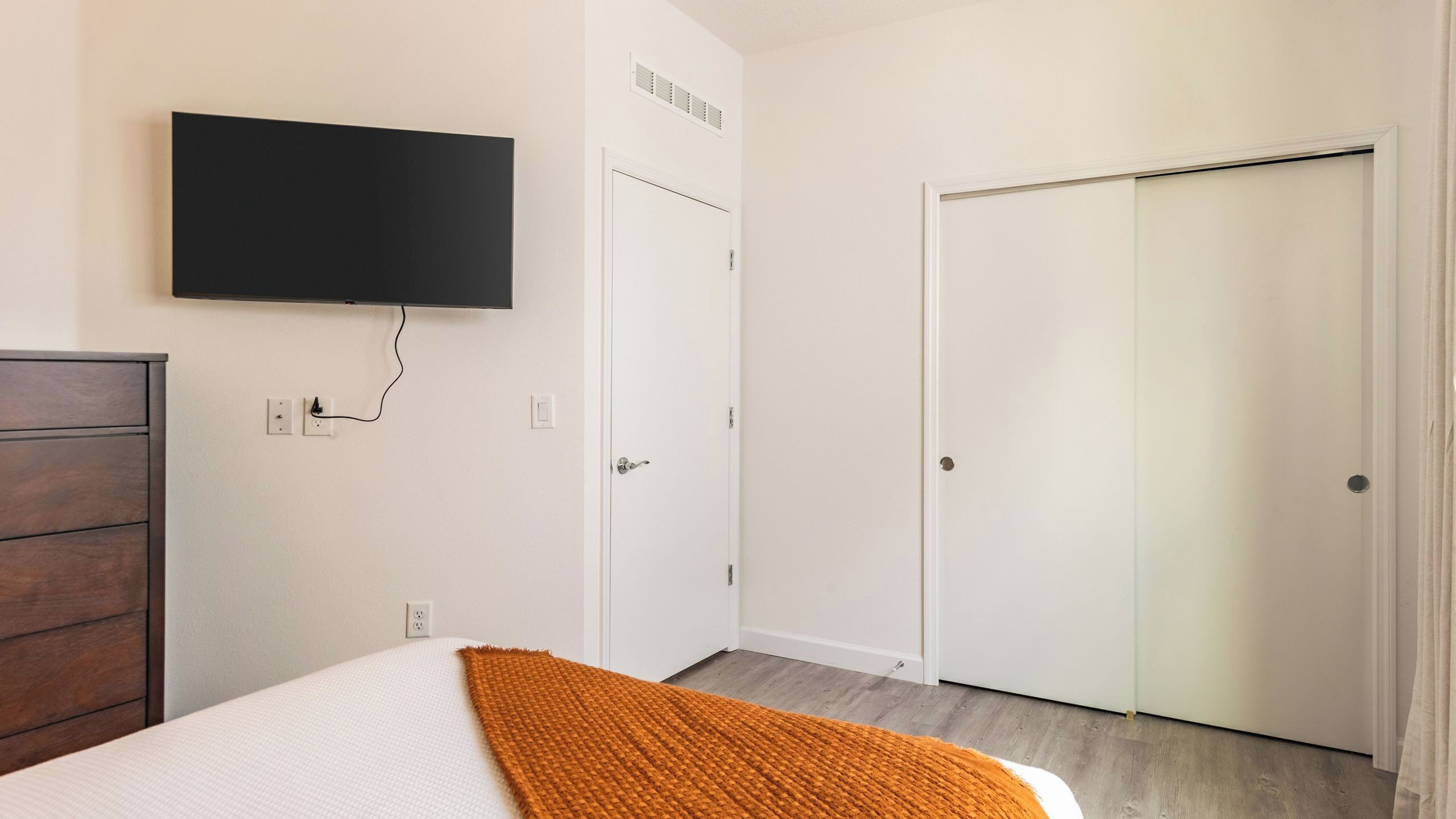 Een slaapkamer met een bed, een televisie aan de muur, een kledingkast en een deur.