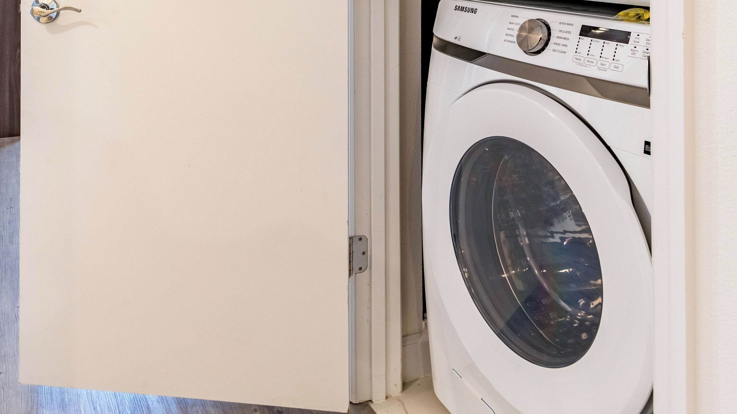 A white door with a silver handle and a white washing machine with a control panel.