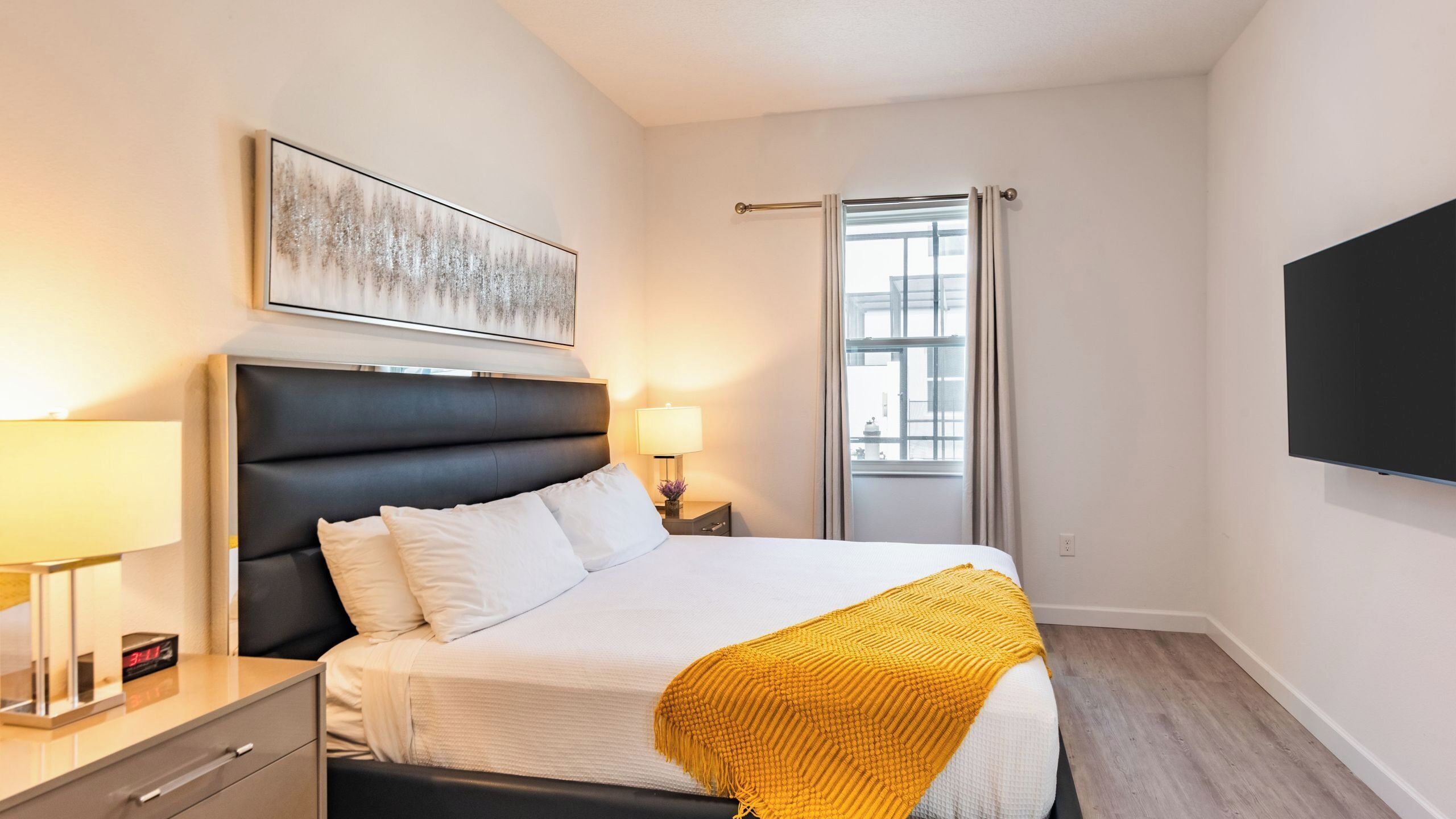 Une chambre d’hôtel avec un lit, une table de chevet, une lampe et une grande fenêtre.