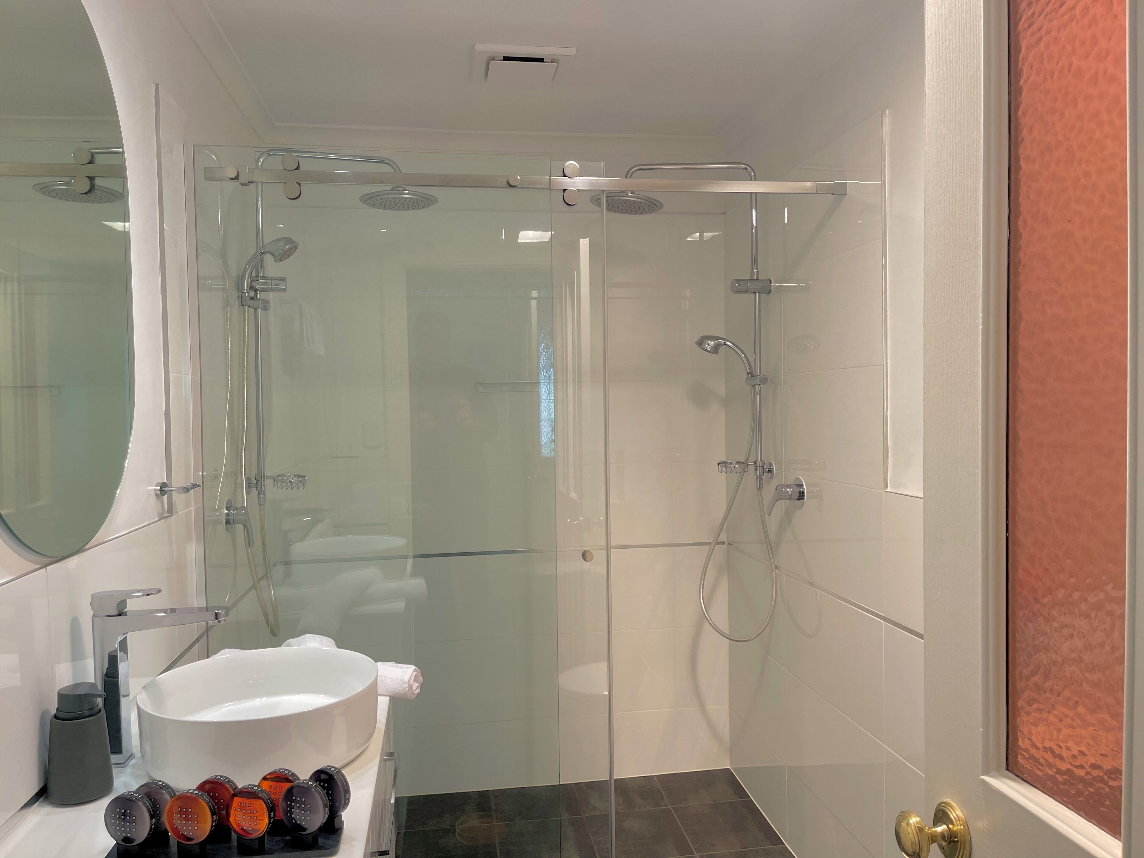 Un baño moderno con ducha acristalada, lavabo blanco y retrete.