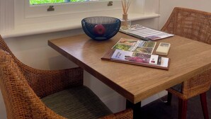 A dining area with a table, wicker chairs, a window with a view of a vineyard, and a decorative bowl. - Pirathon Country Estate (Tanunda)