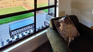 A room with a large window overlooking a landscaped area with a view of hills and a clear sky. - Pirathon Country Estate (Tanunda)