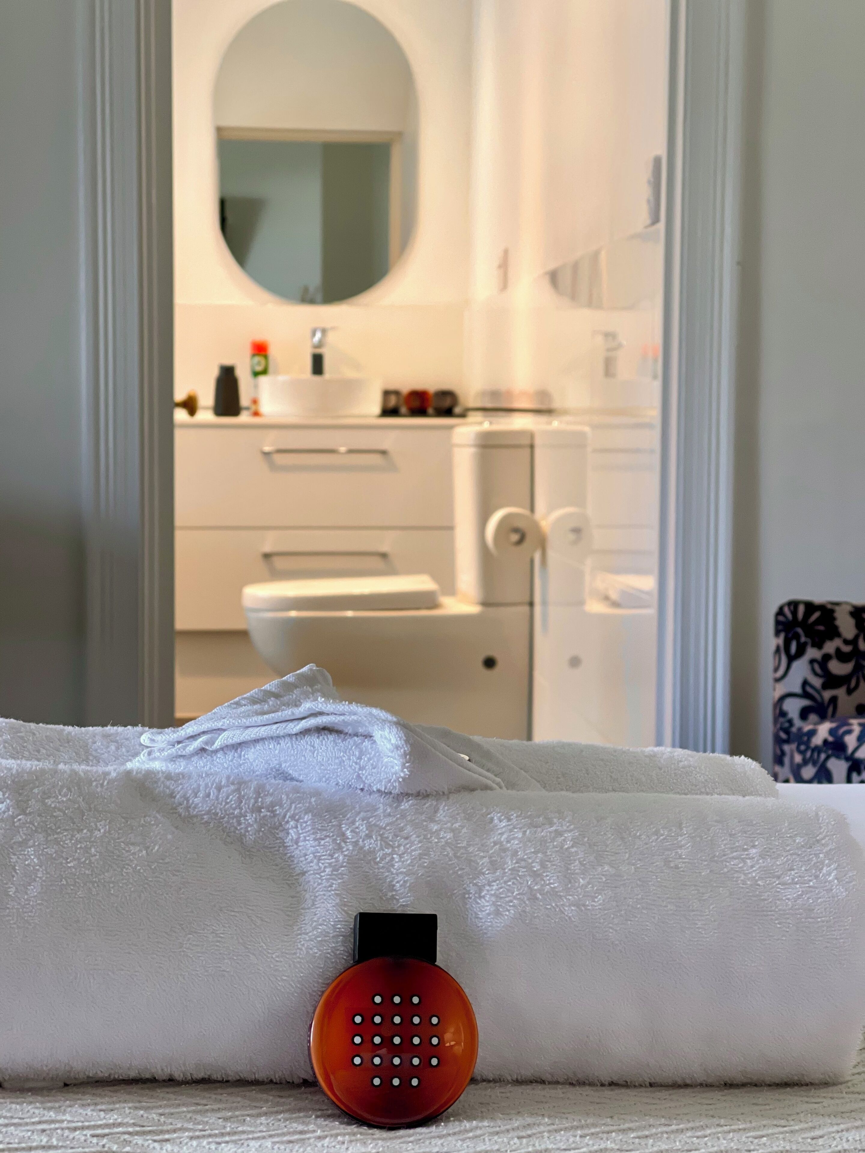 A bathroom with a white sink, mirror, and toilet. A towel is placed on the floor.
