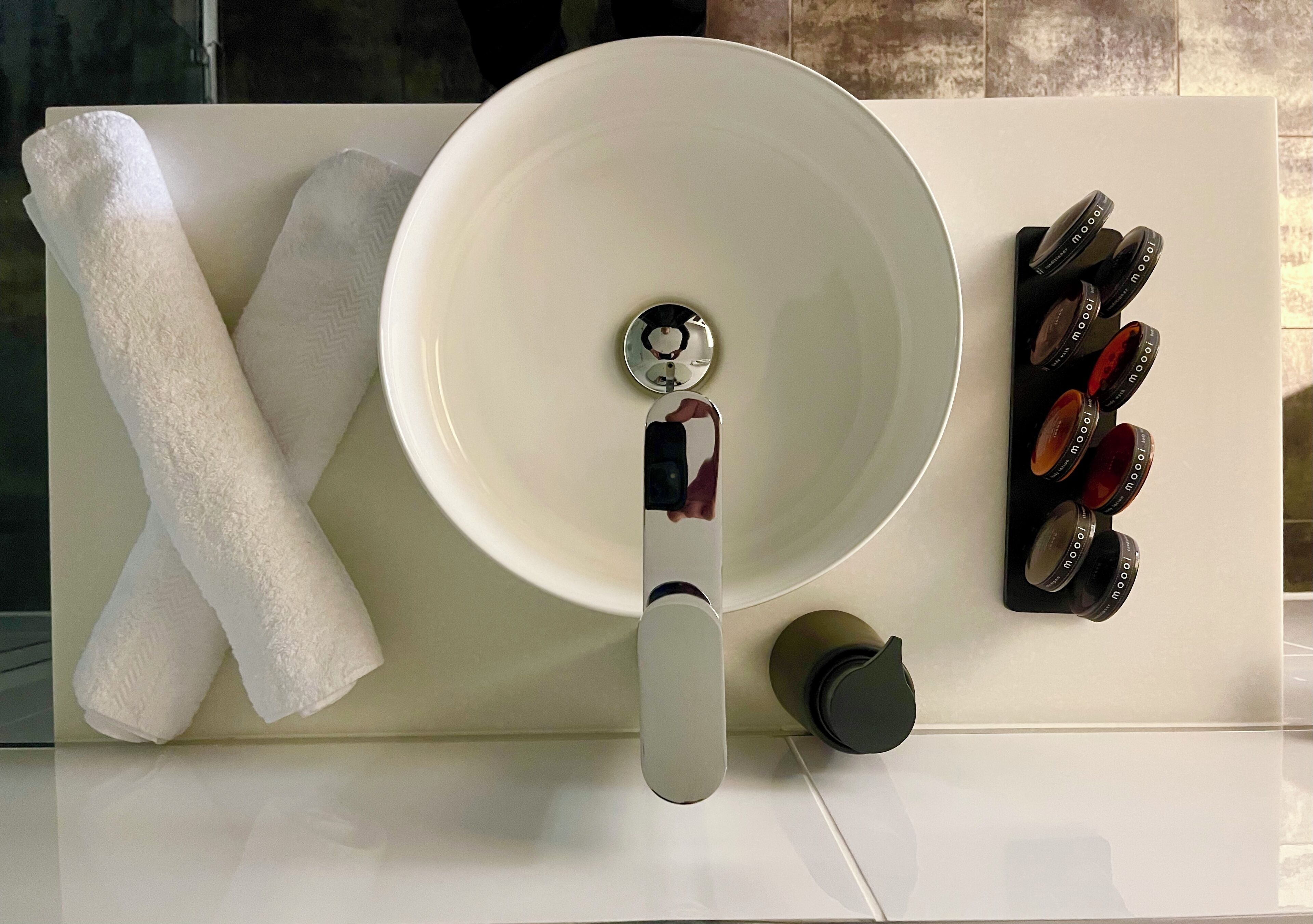 A bathroom with a white sink, a towel, and a soap dispenser.