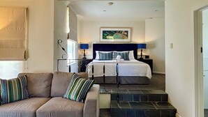 A hotel room with a sofa, a bed with a headboard, a painting on the wall, and a staircase leading to the bedroom. - Pirathon Country Estate (Tanunda)