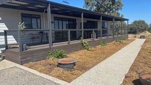 A modern building with a covered outdoor area, a gravel path, and a small garden with plants and a planter. - Pirathon Country Estate (Tanunda)