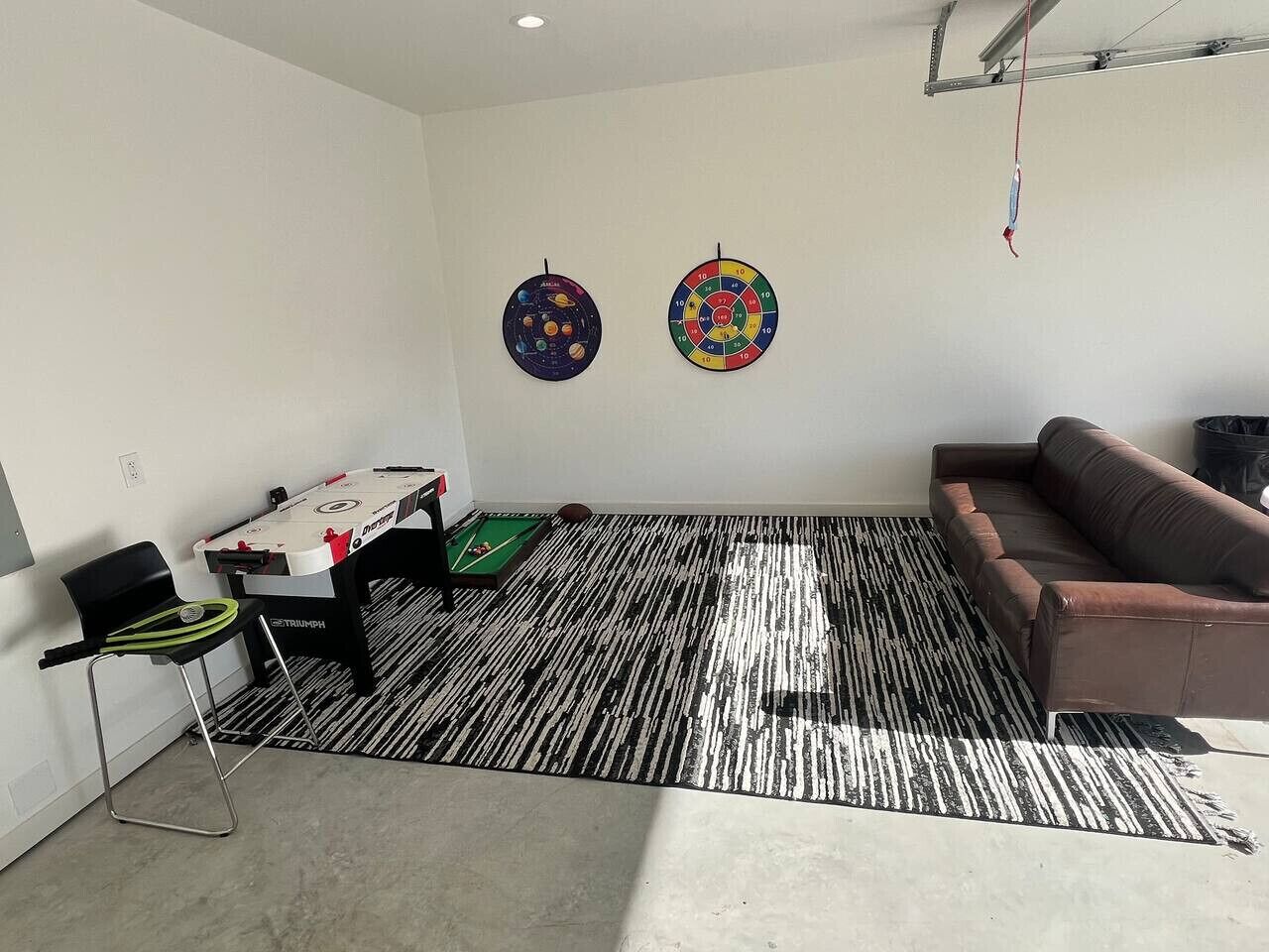 Una habitació amb taula de billar, sofà i dos punts de dardo a la paret.