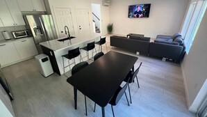 Uma cozinha moderna com armários brancos, uma mesa de jantar preta e uma ilha integrada.