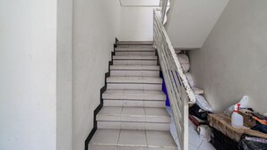 Una escala amb barana blanca que condueix a un replà amb paret blanca i una finestra.