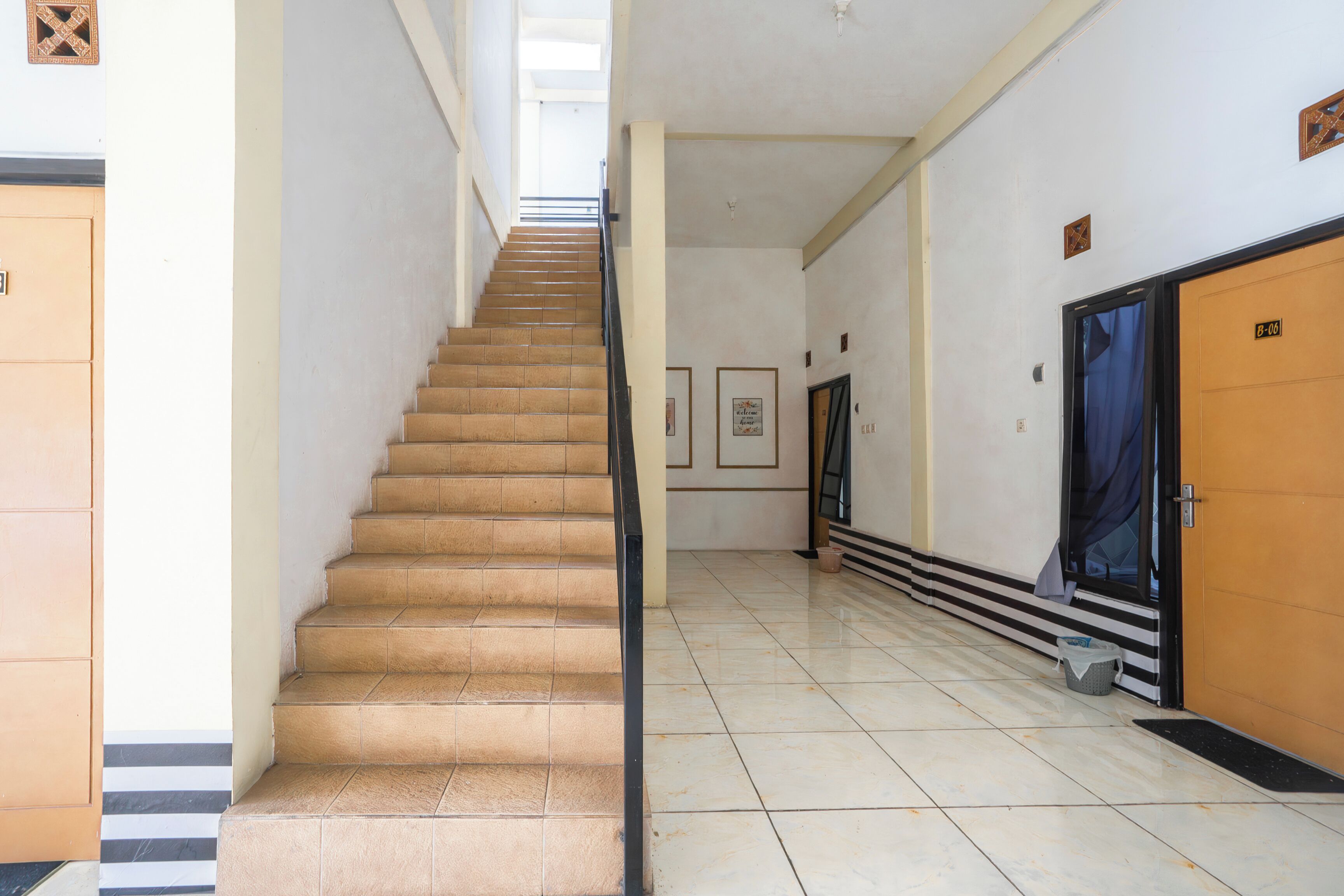 Ein Hotelgang mit einer Treppe, einer Tür mit der Beschriftung "B-10" und einem Mülleimer.