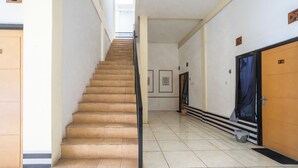 Ένας διάδρομος ξενοδοχείου με μια σκάλα, μια πόρτα με την ένδειξη «Β-10» και έναν κάδο απορριμμάτων.