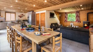 A modern kitchen with a dining area, wooden ceiling, and a cozy living space with a fireplace.