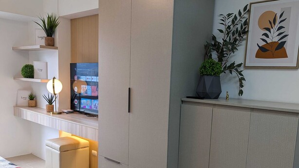Eine moderne Küche mit Einbauofen, ein Essbereich mit Tisch und Stühlen sowie ein an der Wand befestigter Fernseher.