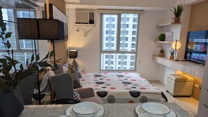 Ein modernes Apartment mit Essbereich, einem Fernseher und einem großen Fenster mit Blick auf die Stadt.