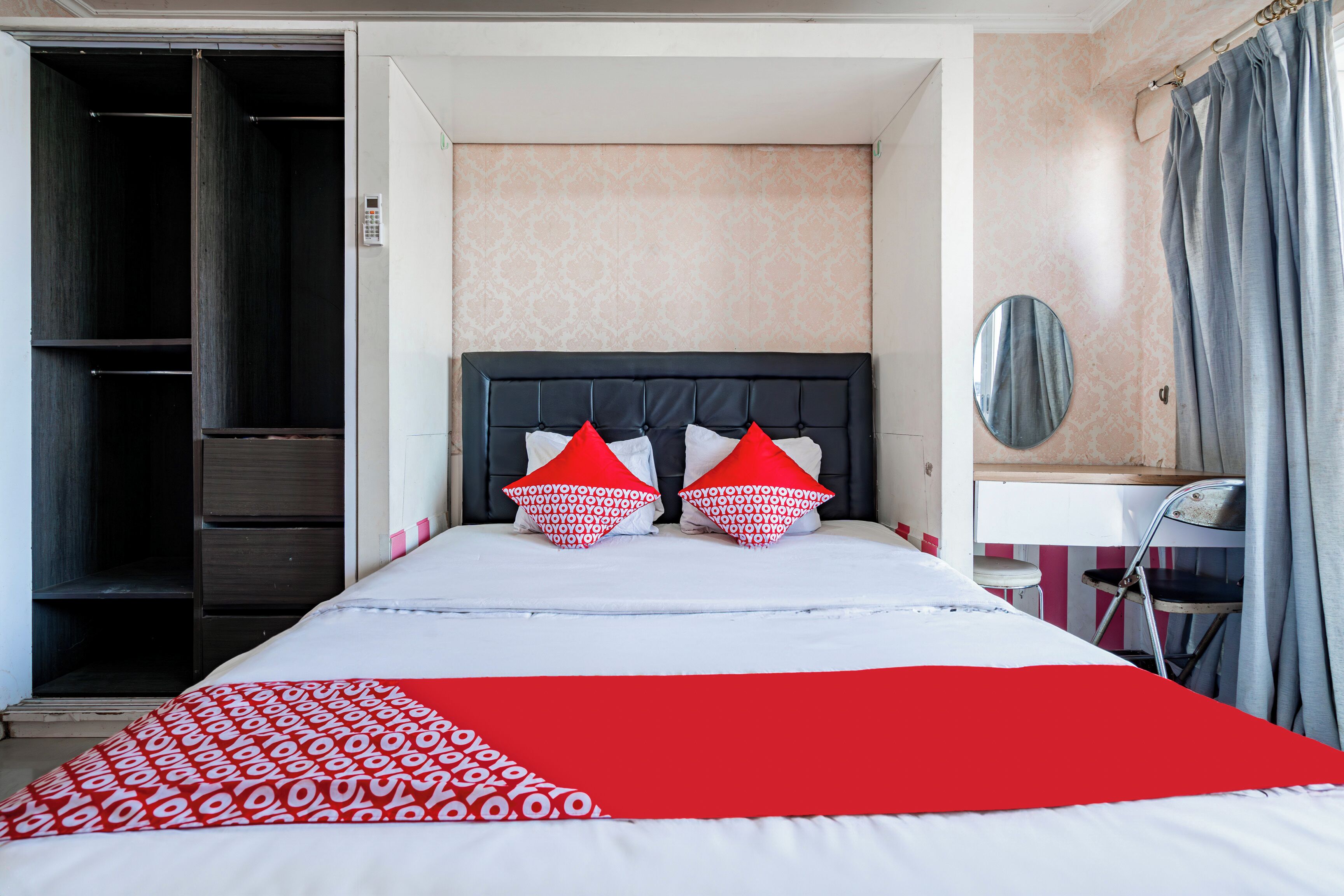 A hotel room with a bed, a wardrobe, a desk, and a mirror.