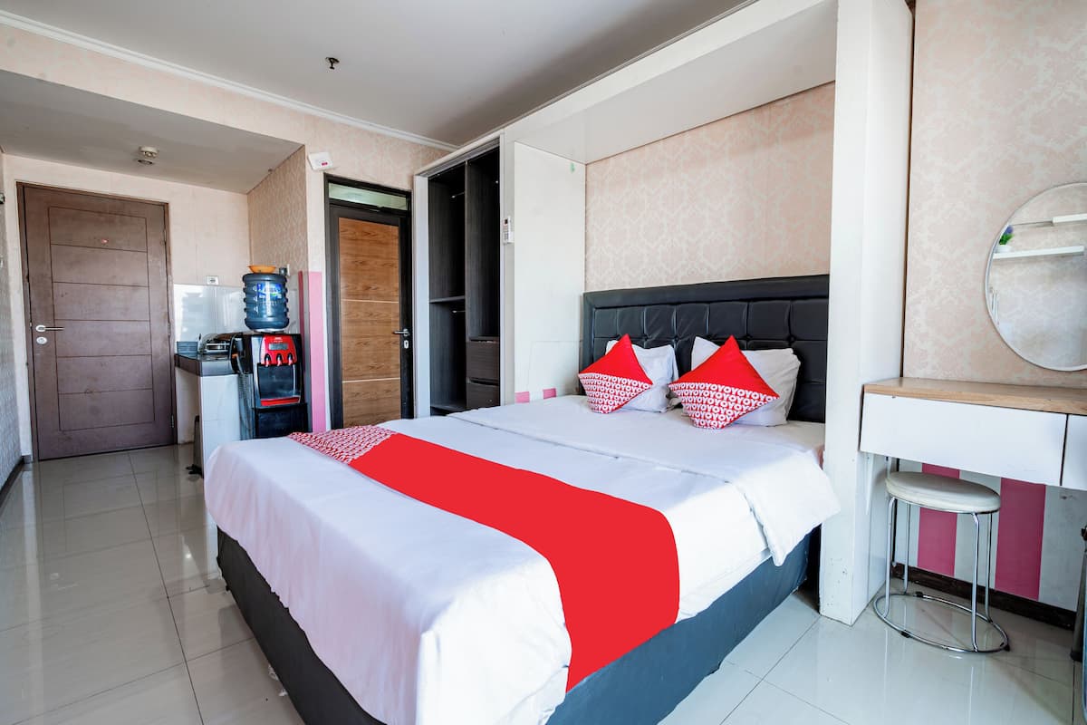 A hotel room with a bed, a desk, a mirror, and a water dispenser.