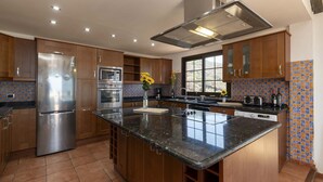 A modern kitchen with wooden cabinets, stainless steel appliances, and a large island.