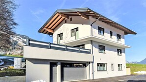 Ein modernes, zweistöckiges Gebäude mit Garage, großen Fenstern und einer flachen Dachfläche.