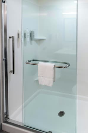 A glass-enclosed shower stall with a towel rack and toiletries. - Home2 Suites BY Hilton Effingham (Effingham)