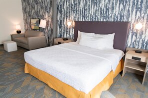 A hotel room with a large bed, a sofa, a nightstand, and a lamp. - Home2 Suites BY Hilton Effingham (Effingham)