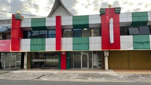 Un edificio con fachada verde y blanca, que destaca una llamativa franja roja.