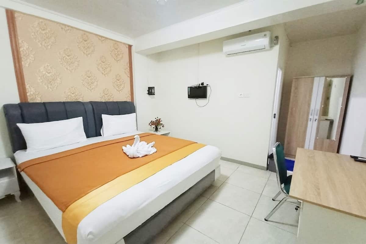Una habitación de hotel con una cama, un escritorio, aire acondicionado y un espejo.