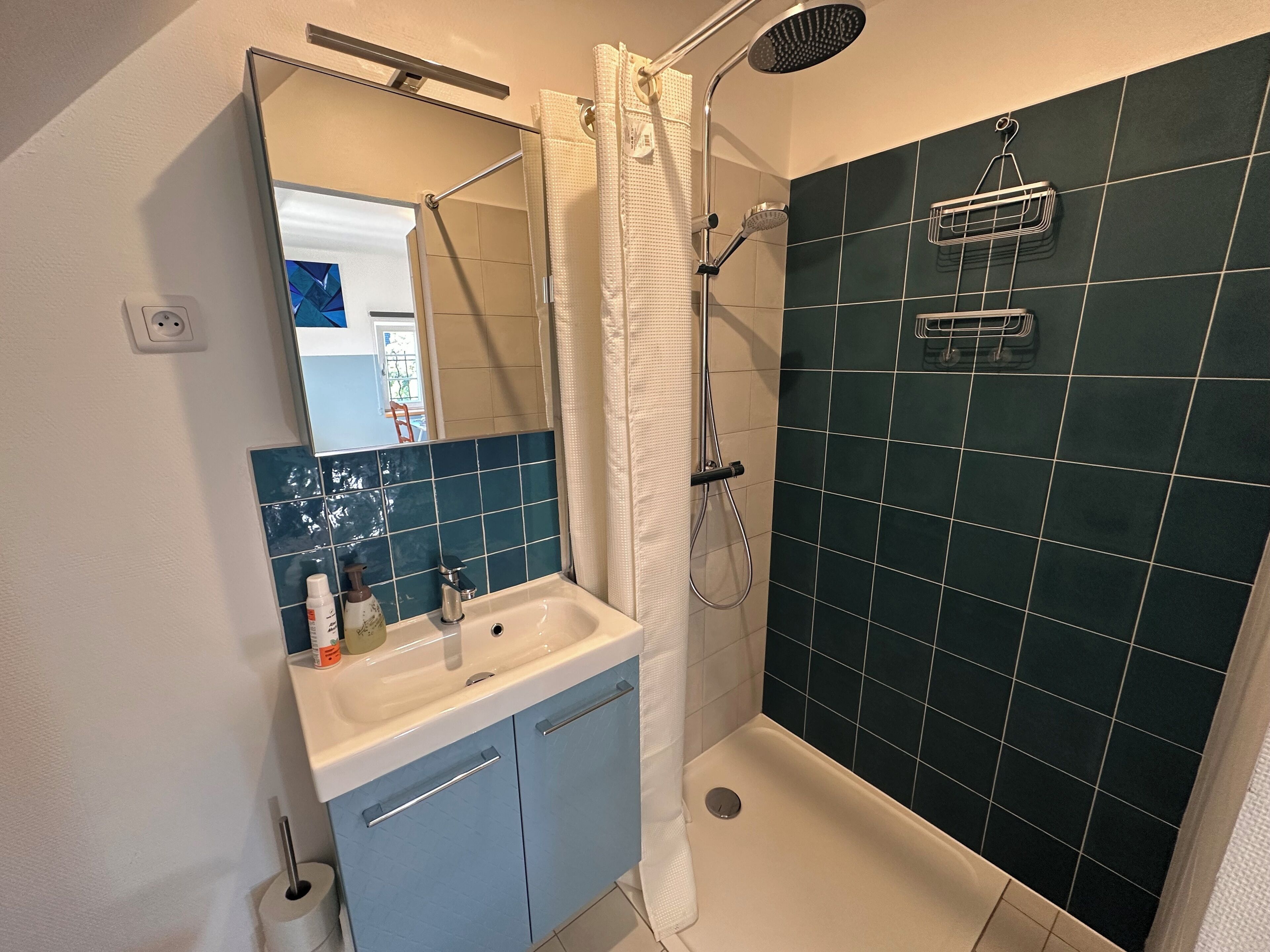 A bathroom with a shower, a sink, and a mirror.