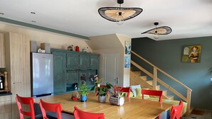 Un comedor con una mesa de madera, sillas rojas y una cocina al fondo.