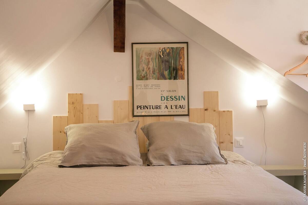 Une chambre à coucher avec une tête de lit en bois, deux oreillers et une affiche accrochée au mur.