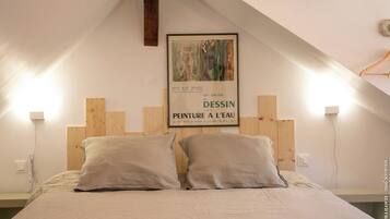 Une chambre à coucher avec une tête de lit en bois, deux oreillers et une affiche accrochée au mur.