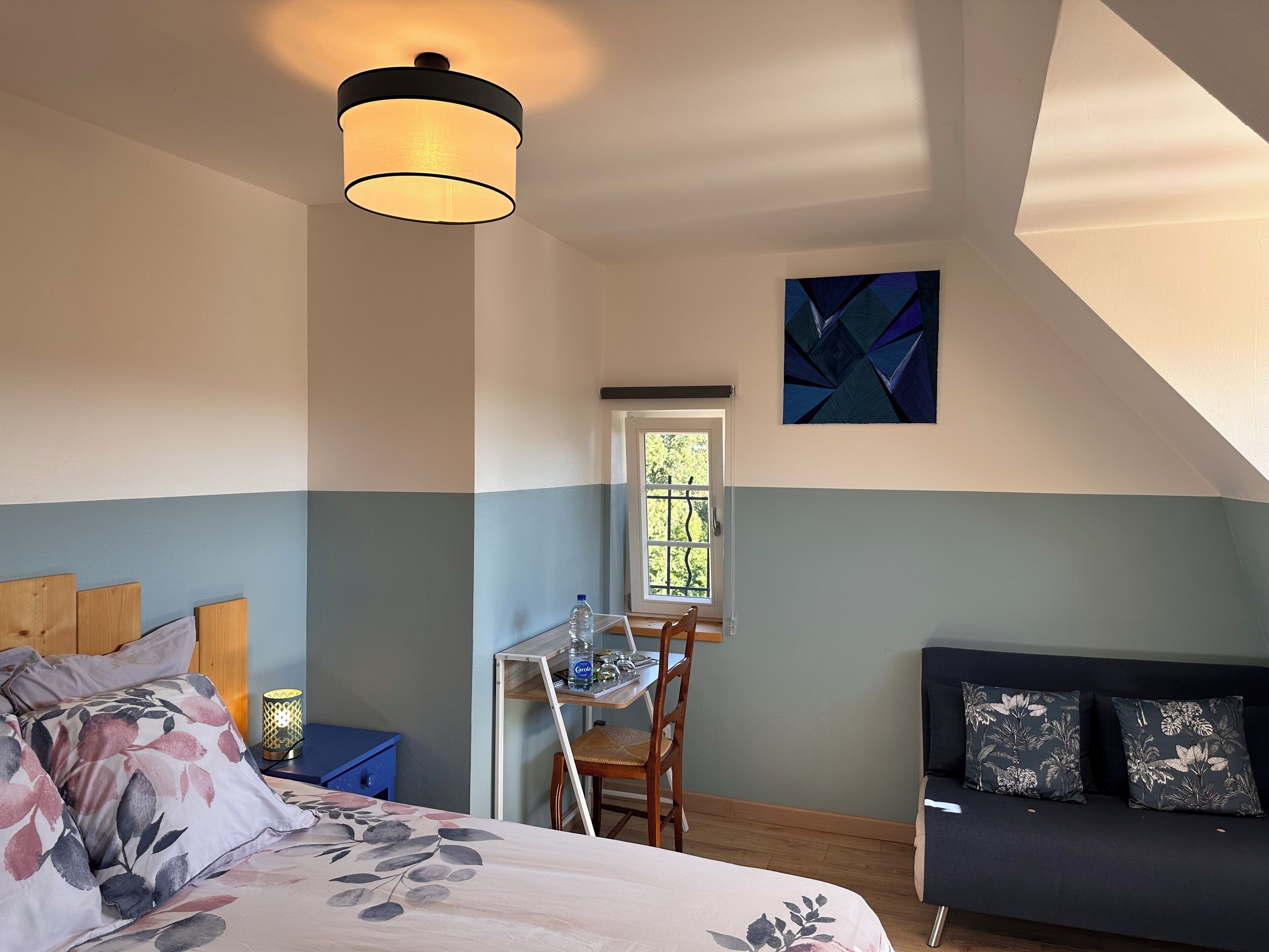 Een slaapkamer met een bed, een bureau, een stoel, een bank en een raam.
