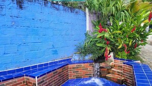 Ein Bereich mit blau gefliestem Whirlpool, einer Ziegelwand und einem kleinen Wasserfall.