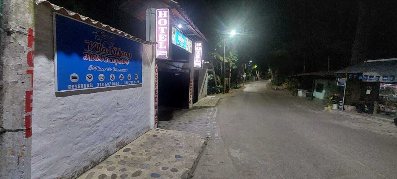 Entrada de un hotel con un letrero que muestra el nombre y la información de contacto.