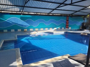 Una piscina con plataforma azulejada y pared con diseño de olas azules.