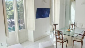 A bright room with a glass dining table, white walls, and large windows.