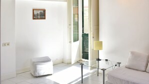 A modern room with a white sofa, a glass table, and a wooden ceiling.