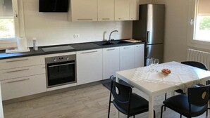 A modern kitchen with white cabinets, a stainless steel refrigerator, a built-in oven, and a dining table with chairs. - RENTAL ROOMS "AT THE GRANDFATHER'S HOUSE" convenient, strategic and quiet site (Campodarsego)
