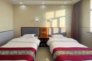 Habitación de hotel con dos camas, cabecero de madera, mesita de noche y ventana con cortinas.