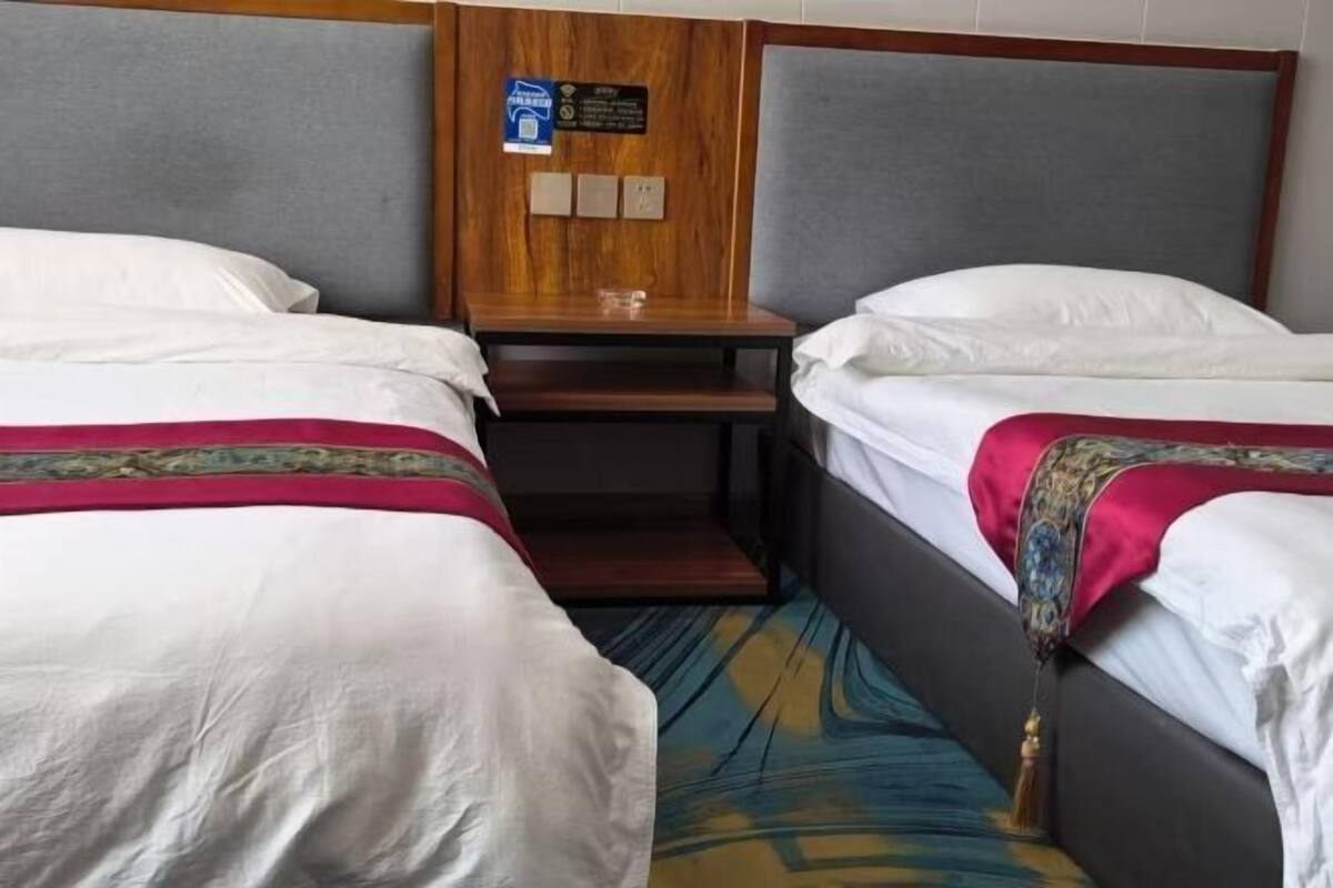 A hotel room with two single beds, a wooden nightstand, and a small table.