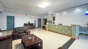 A hotel lobby with a reception desk, seating area, and a large illuminated ceiling light. - Hailar Dongsheng Luxury Hotel (Hailar Airport Branch) (Hulunbuir)